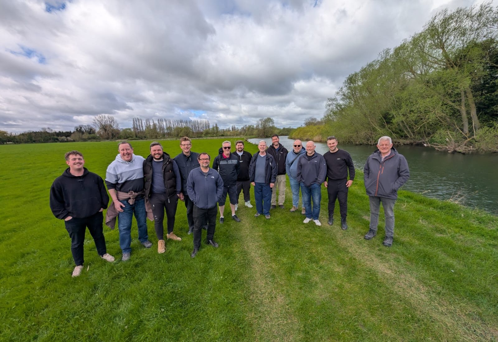 A group of men standing together on the riverbank near St Ives after a walk.